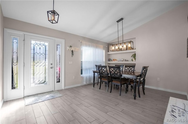 dining area featuring hardwood / wood-style flooring, vaulted ceiling, and a chandelier