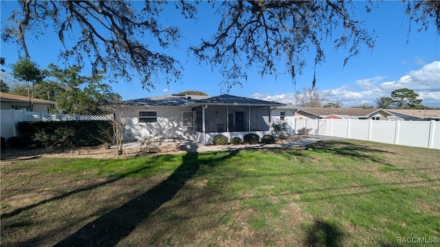 rear view of house featuring a sunroom and a yard