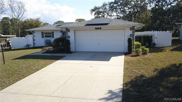 single story home featuring a garage, a front yard, and solar panels