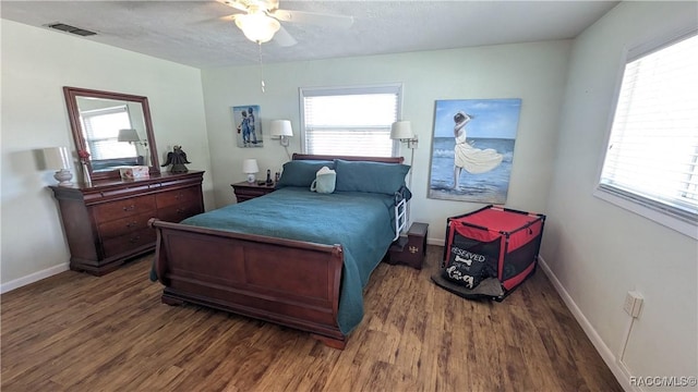 bedroom featuring multiple windows, dark hardwood / wood-style floors, and a textured ceiling