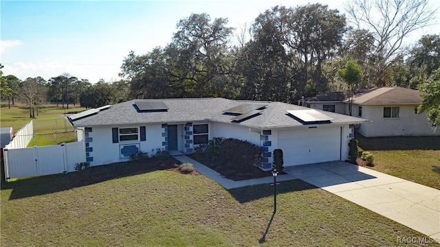 view of front of property featuring a garage, a front lawn, and solar panels