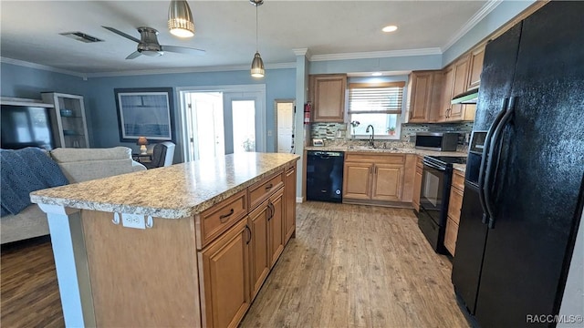 kitchen featuring sink, crown molding, light wood-type flooring, a kitchen island, and black appliances