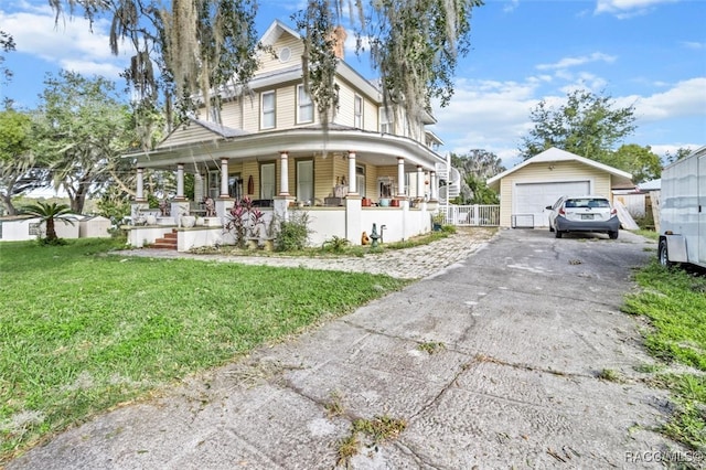 view of front of home with an outbuilding, a porch, a garage, and a front lawn