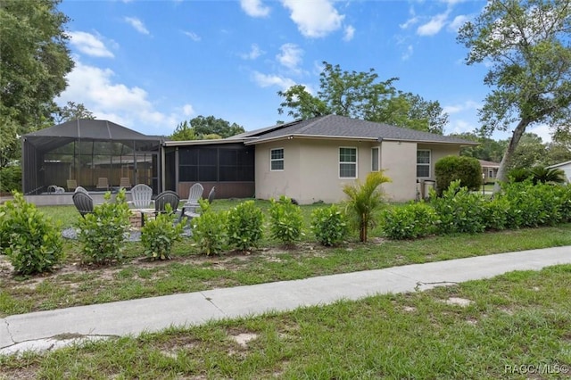 9125 N Abbot Dr, Citrus Springs, FL 34434 - back of property with stucco siding, roof mounted solar panels, a yard, and a sunroom