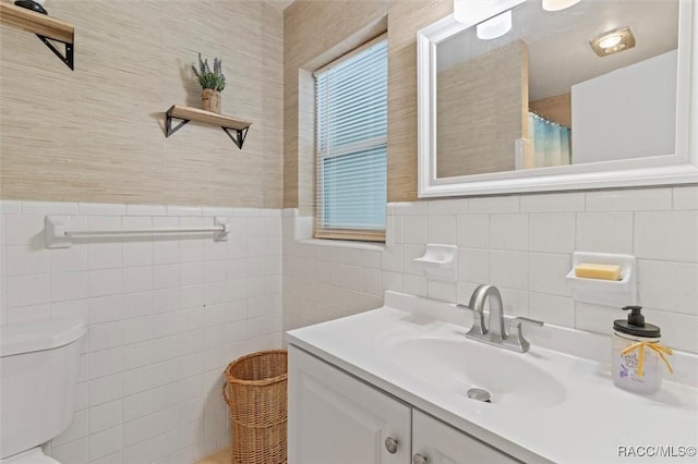 9125 N Abbot Dr, Citrus Springs, FL 34434 - bathroom with tile walls, toilet, vanity, a wainscoted wall, and wallpapered walls