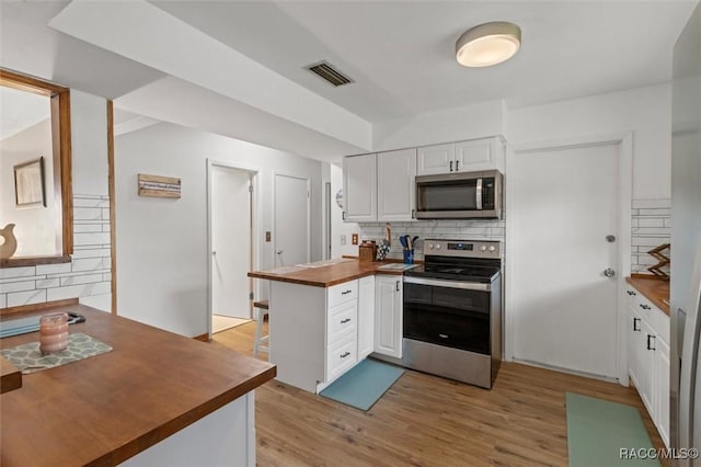 9125 N Abbot Dr, Citrus Springs, FL 34434 - kitchen with appliances with stainless steel finishes, wooden counters, tasteful backsplash, white cabinetry, and light wood finished floors