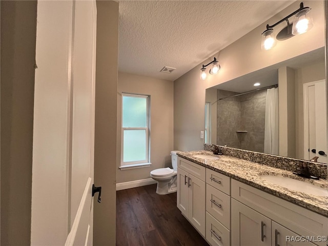 bathroom with vanity, a textured ceiling, wood-type flooring, toilet, and curtained shower