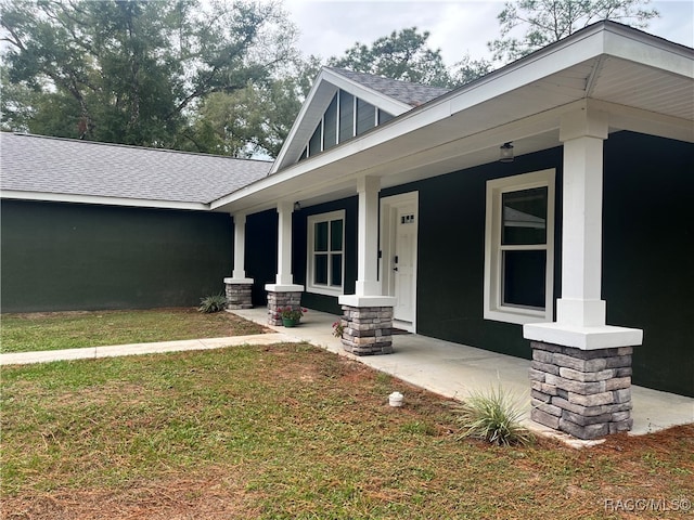 doorway to property with a lawn and a porch