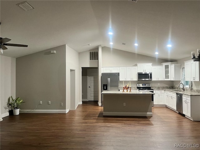 kitchen with appliances with stainless steel finishes, a kitchen island, dark hardwood / wood-style floors, white cabinetry, and lofted ceiling