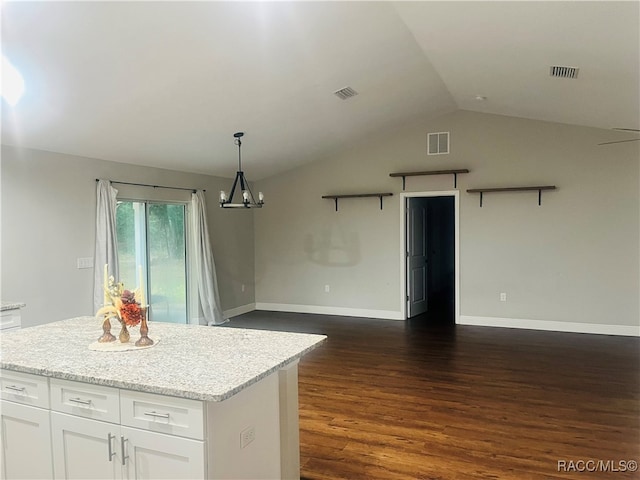 kitchen featuring light stone counters, vaulted ceiling, dark wood-type flooring, decorative light fixtures, and white cabinets