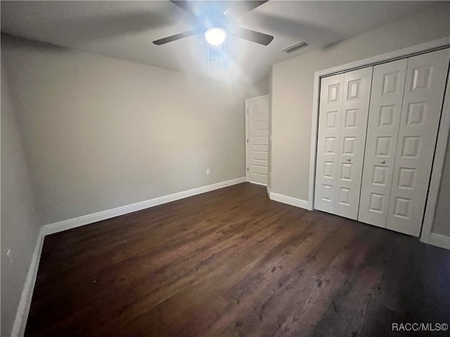 unfurnished bedroom with ceiling fan, dark wood-type flooring, and a closet