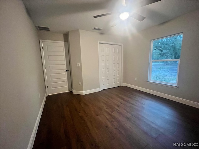 unfurnished bedroom featuring a closet, ceiling fan, and dark wood-type flooring