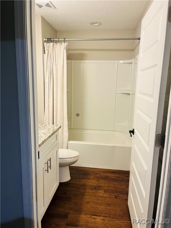 full bathroom with hardwood / wood-style floors, shower / bath combination with curtain, a textured ceiling, toilet, and vanity