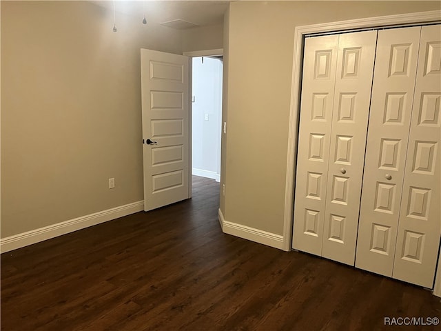 unfurnished bedroom with dark hardwood / wood-style flooring and a closet