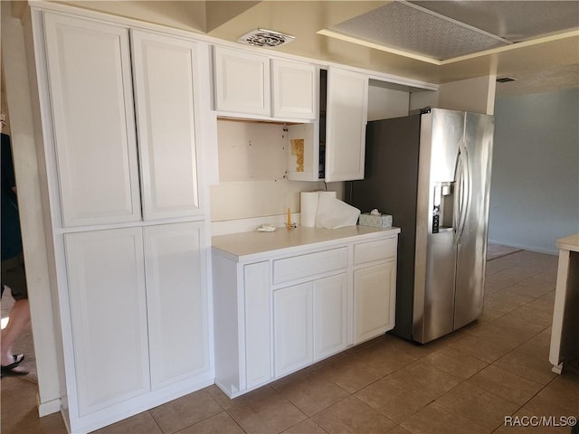 kitchen with stainless steel refrigerator with ice dispenser, light tile patterned floors, and white cabinets