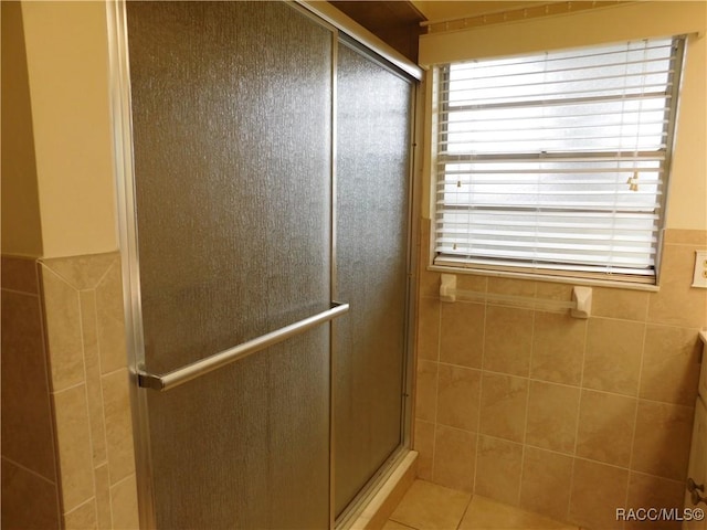 bathroom featuring tile walls, tile patterned floors, and a shower with door