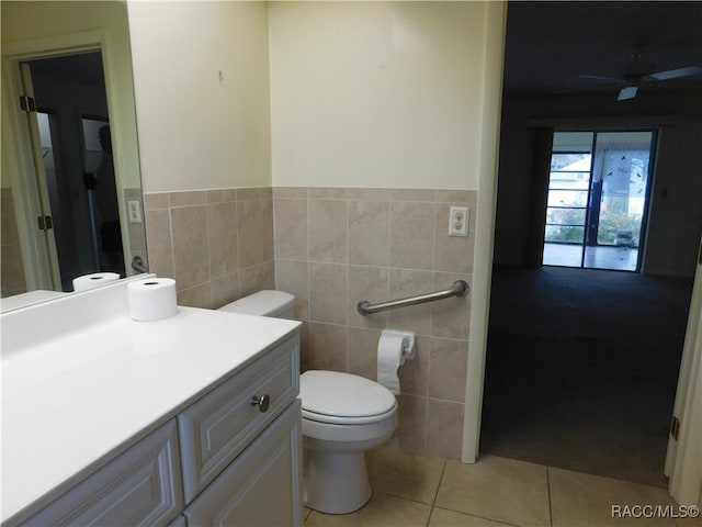 bathroom with ceiling fan, tile walls, vanity, tile patterned floors, and toilet