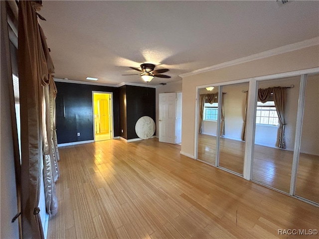 unfurnished living room with crown molding, ceiling fan, and light wood-type flooring