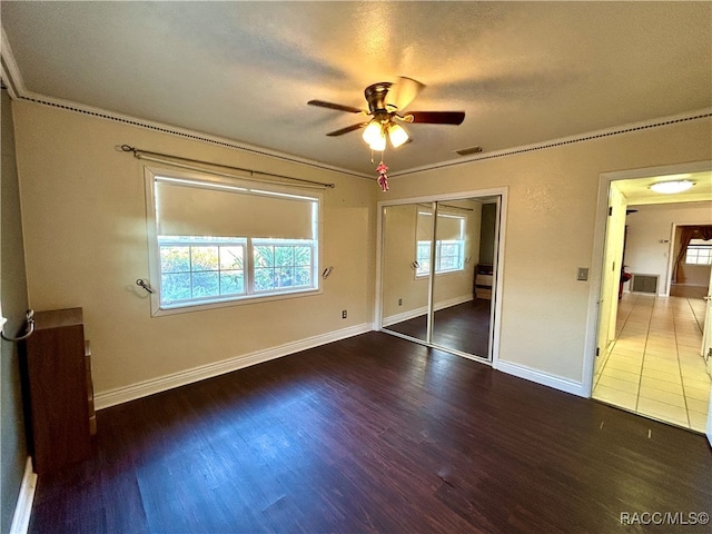 unfurnished bedroom featuring a textured ceiling, dark hardwood / wood-style flooring, a closet, and ceiling fan