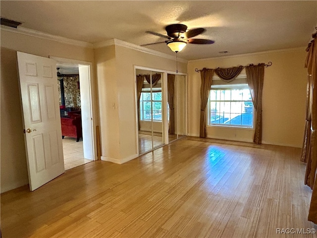 empty room featuring a wealth of natural light, light hardwood / wood-style flooring, ceiling fan, and ornamental molding