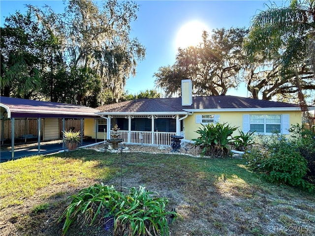 rear view of property with a carport, a porch, and a lawn