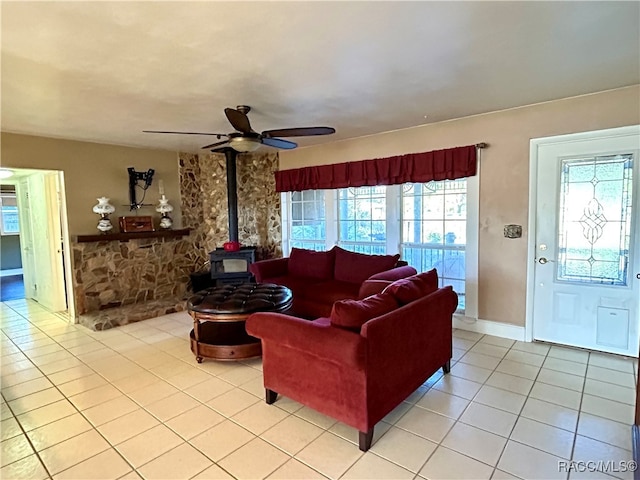 tiled living room with a wood stove, plenty of natural light, and ceiling fan