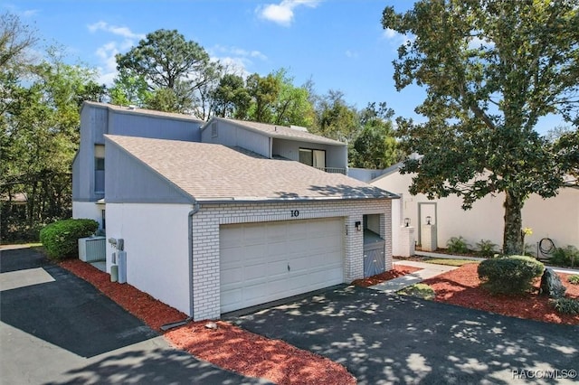 view of front of house with a garage, driveway, brick siding, and roof with shingles