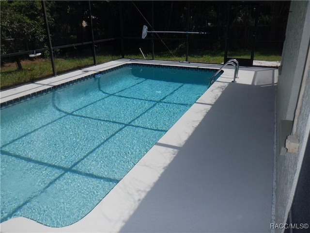 view of swimming pool featuring glass enclosure