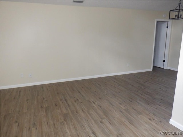 spare room featuring an inviting chandelier and hardwood / wood-style floors