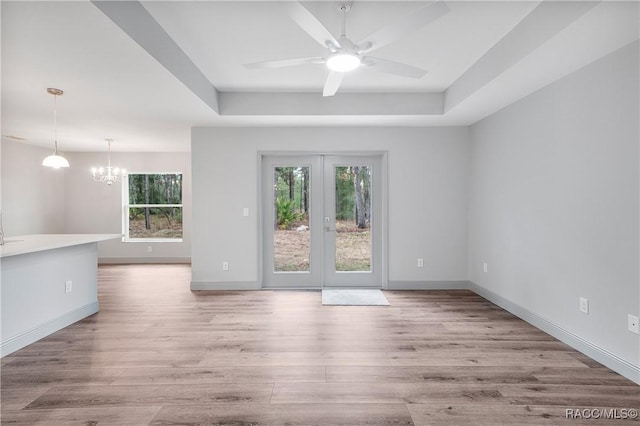 unfurnished room with a tray ceiling, wood finished floors, and a healthy amount of sunlight