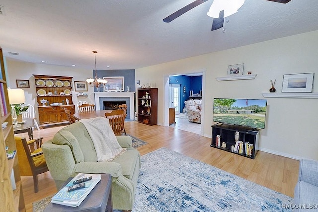 living room with visible vents, baseboards, ceiling fan with notable chandelier, and wood finished floors