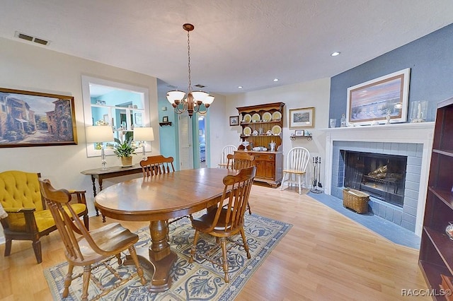 dining room with an inviting chandelier, recessed lighting, a fireplace with flush hearth, light wood-type flooring, and visible vents