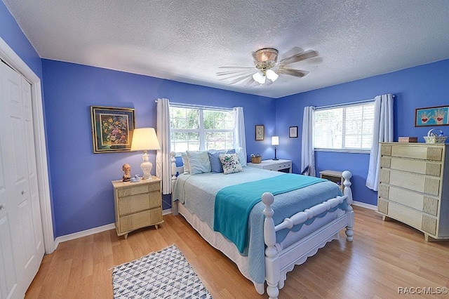 bedroom featuring baseboards, a ceiling fan, a textured ceiling, and light wood finished floors
