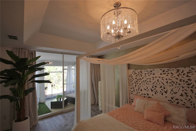 bedroom featuring hardwood / wood-style floors, access to exterior, and a chandelier