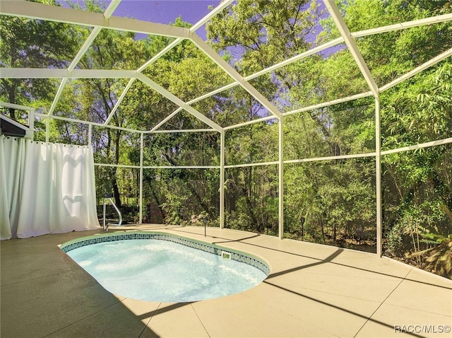 view of pool with a patio area and glass enclosure