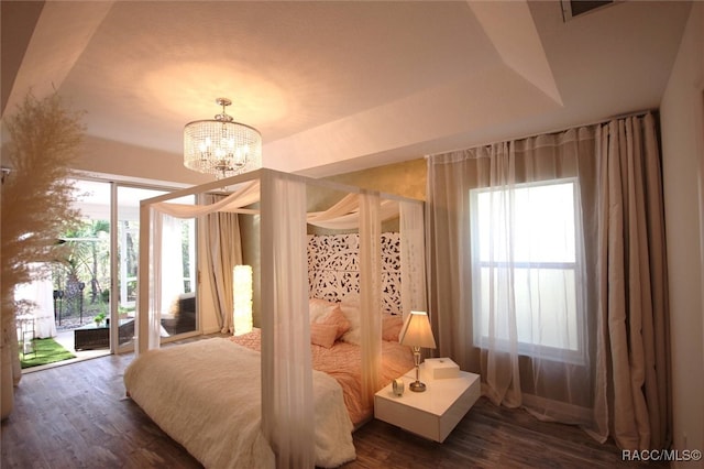 bedroom with access to outside, multiple windows, dark hardwood / wood-style flooring, and an inviting chandelier