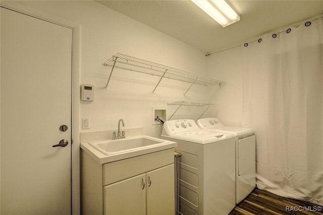 laundry area featuring a textured ceiling, dark hardwood / wood-style flooring, washing machine and dryer, and sink