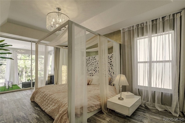 bedroom with hardwood / wood-style flooring, a chandelier, lofted ceiling, and multiple windows