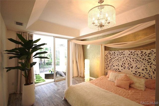 bedroom with access to exterior, hardwood / wood-style floors, and a chandelier