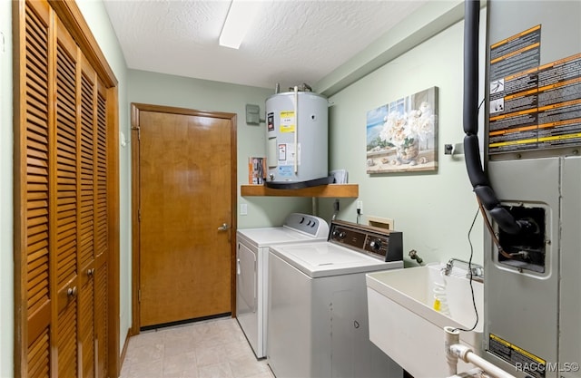 laundry room with sink, washing machine and clothes dryer, a textured ceiling, and water heater