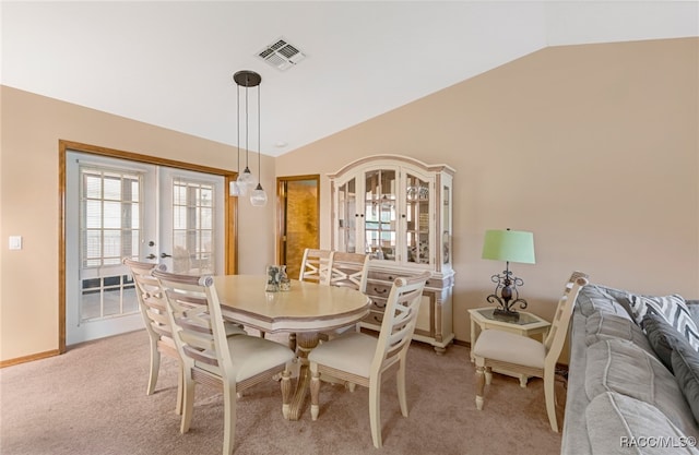 carpeted dining room with french doors and lofted ceiling