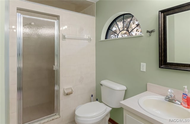 bathroom with vanity, toilet, and a shower with door