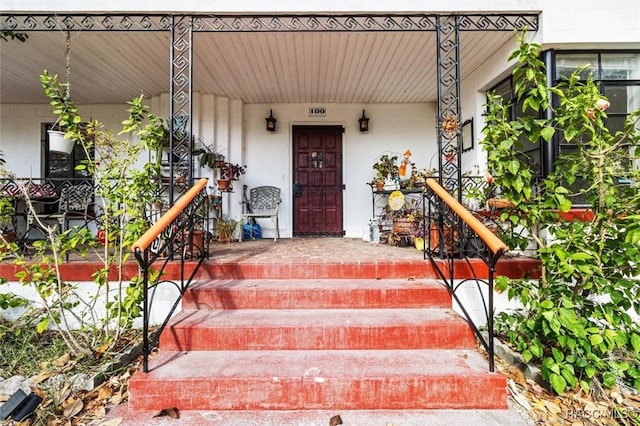 entrance to property featuring covered porch and stucco siding