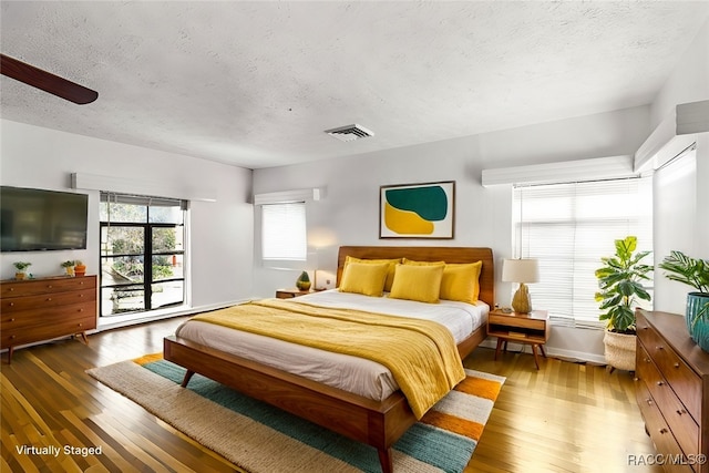 bedroom with a textured ceiling, ceiling fan, and dark wood-type flooring