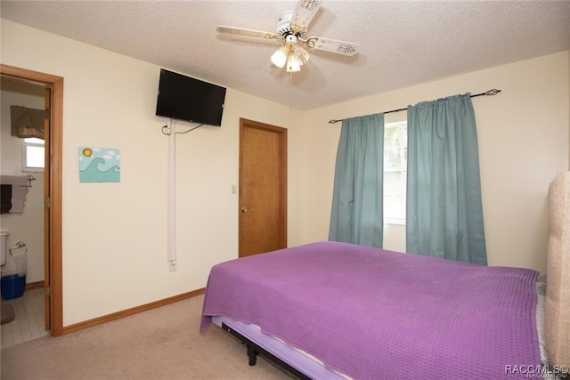 bedroom with carpet flooring, a textured ceiling, ensuite bathroom, and ceiling fan