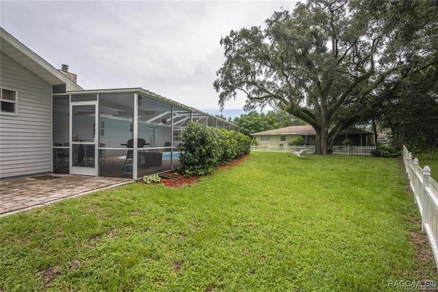 view of yard featuring a sunroom, glass enclosure, and a patio