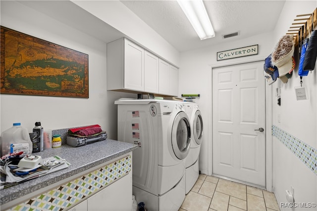 clothes washing area featuring washer and dryer, light tile patterned flooring, cabinets, and a textured ceiling