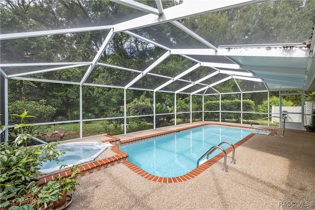 view of pool featuring glass enclosure, a patio area, and an in ground hot tub