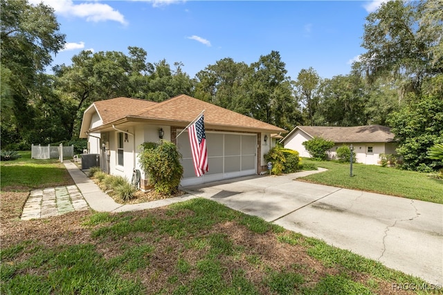 view of front facade with a front yard, a garage, and central AC unit