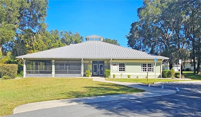 view of front facade with a sunroom, a front yard, and french doors